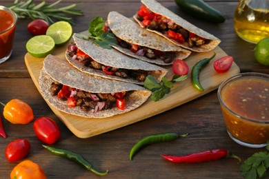Delicious tacos with meat and vegetables on wooden table