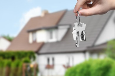 Image of Woman holding key near house outdoors, closeup