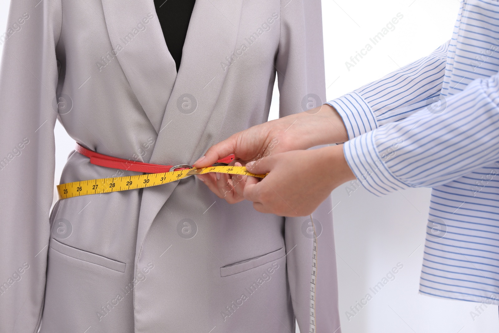 Photo of Tailor measuring jacket on mannequin in workshop, closeup