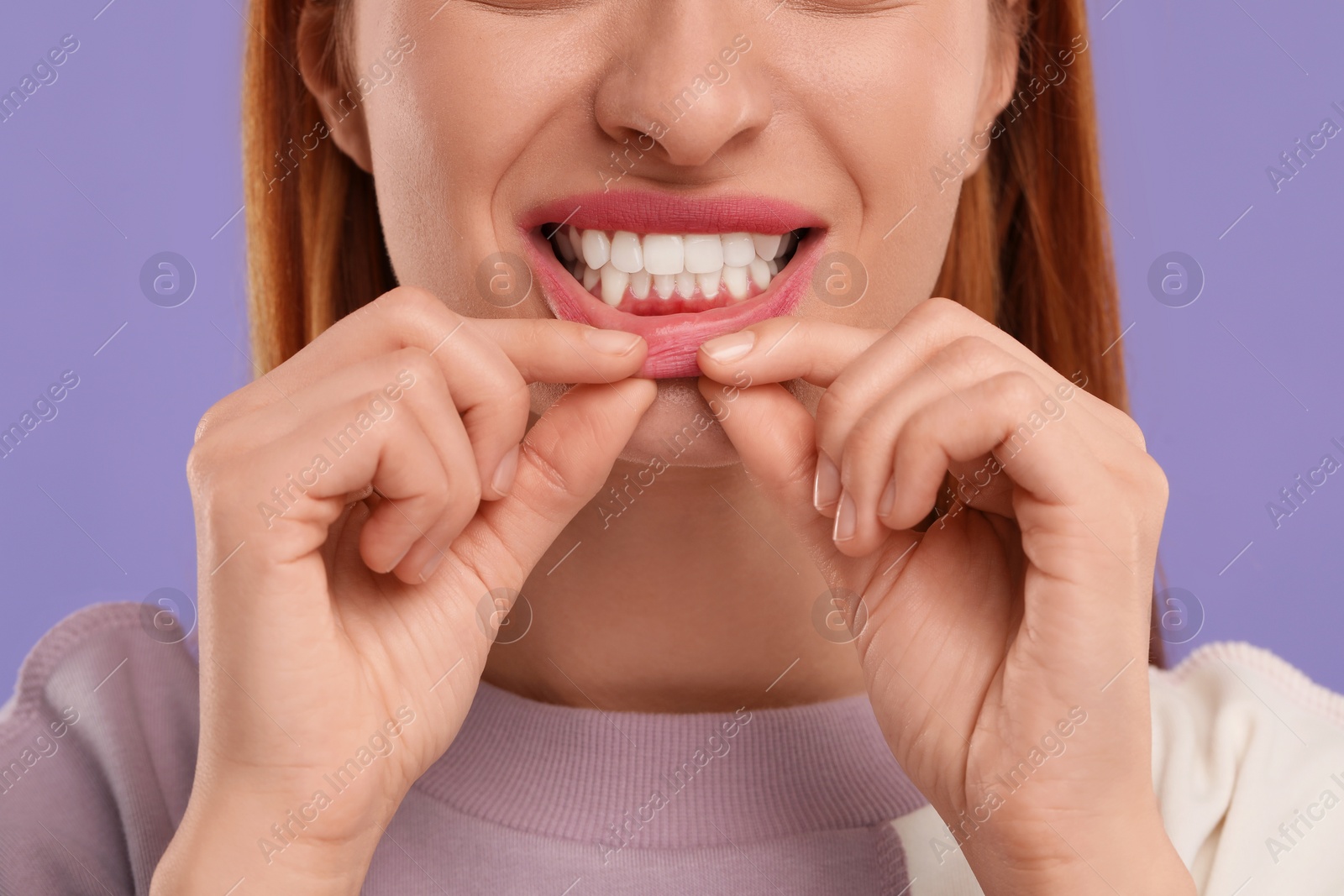 Photo of Woman showing her clean teeth on violet background, closeup