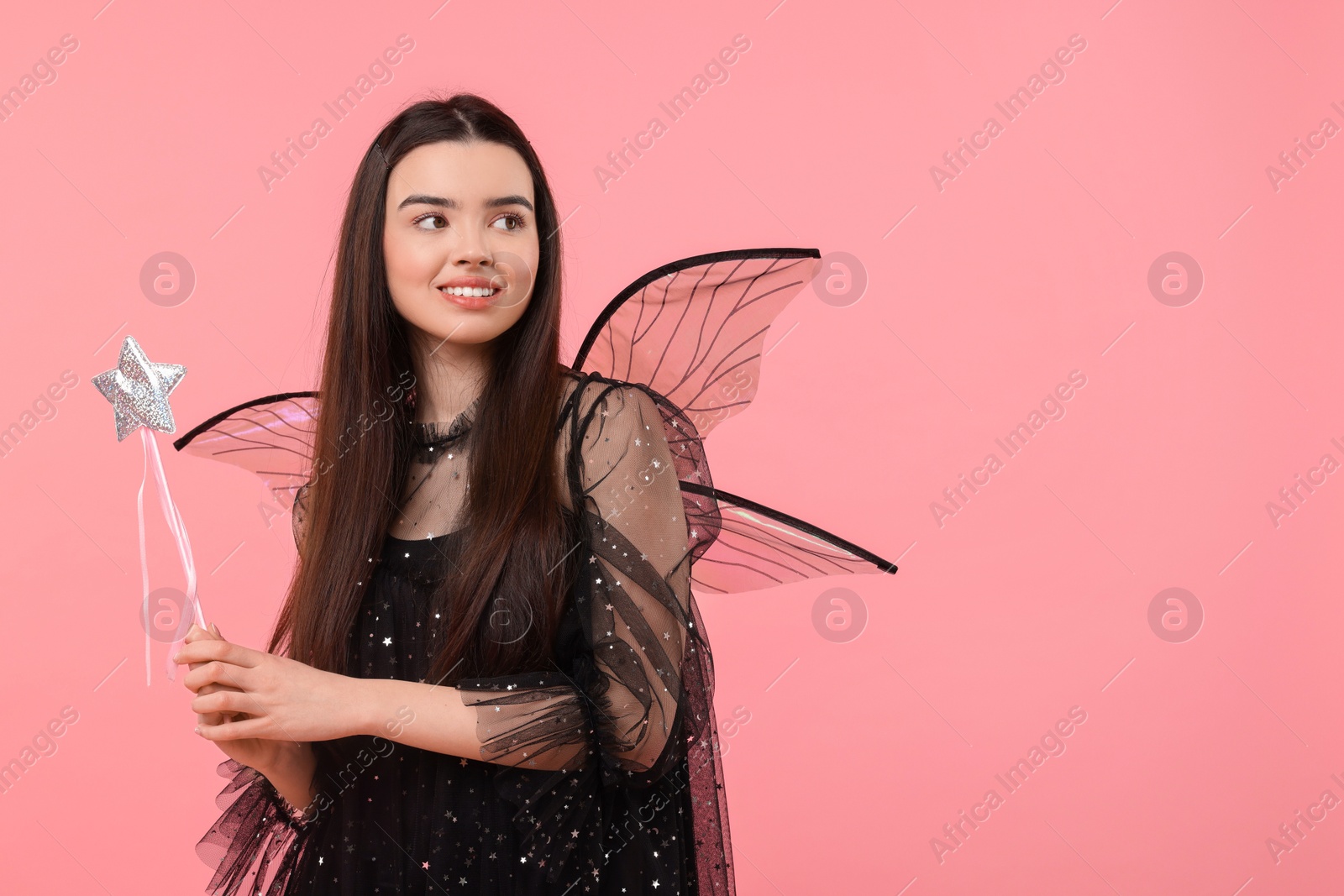 Photo of Beautiful girl in fairy costume with wings and magic wand on pink background, space for text