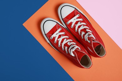 Photo of Pair of new stylish red sneakers on colorful background, flat lay. Space for text