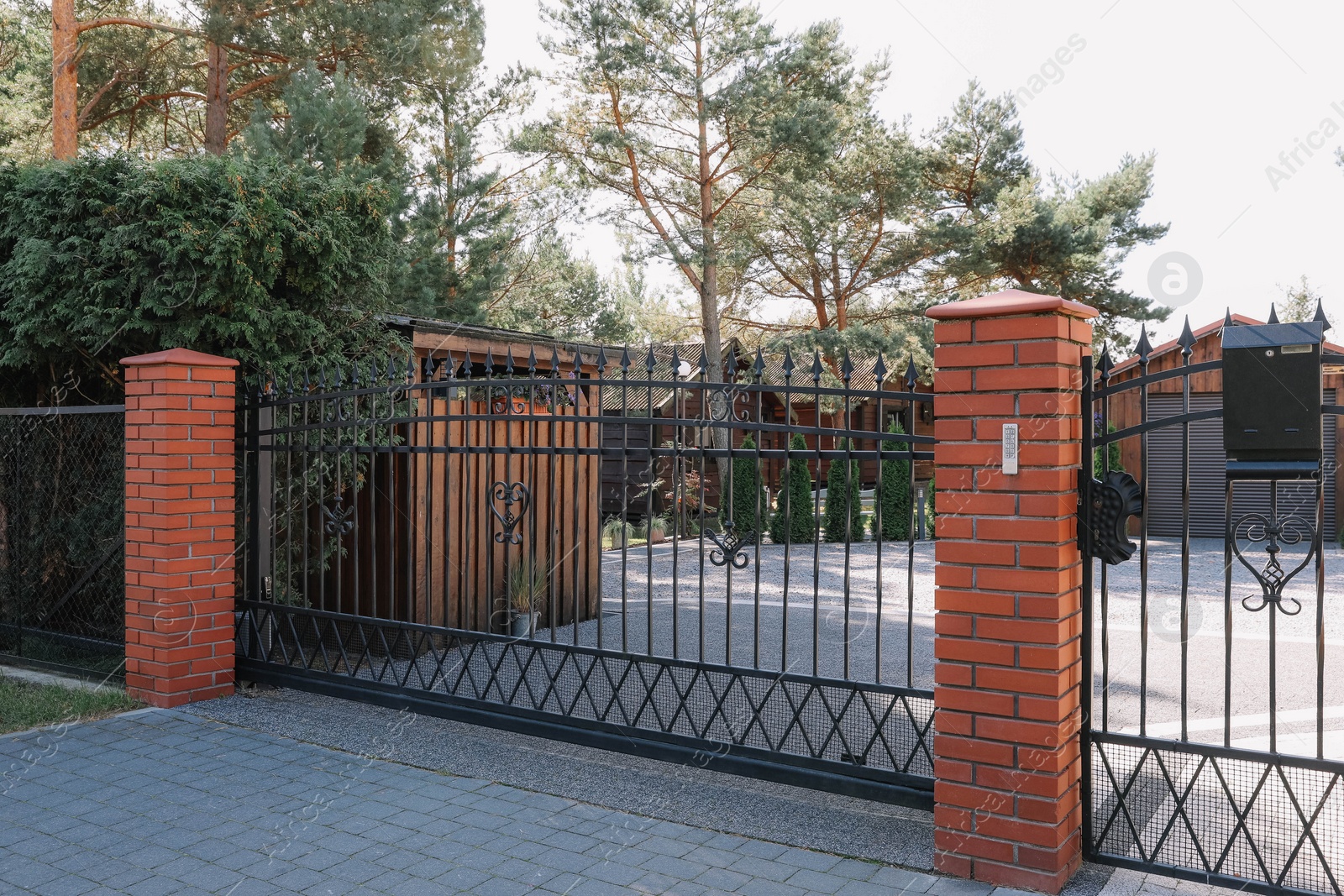 Photo of Metal gates near beautiful trees and houses on sunny day