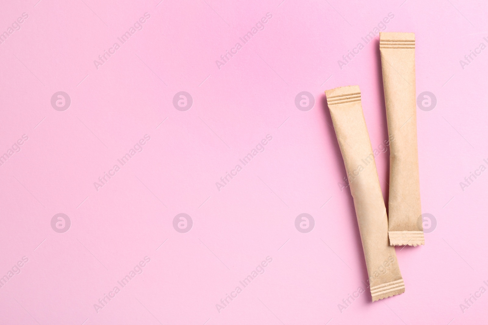 Photo of Beige sticks of sugar on pink background, flat lay. Space for text