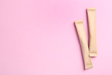 Beige sticks of sugar on pink background, flat lay. Space for text
