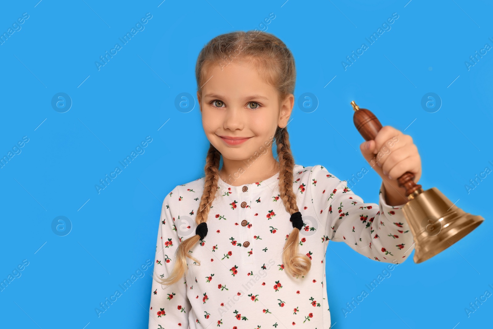 Photo of Pupil with school bell on light blue background