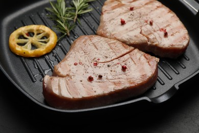 Photo of Delicious tuna steaks with lemon and rosemary on table, closeup