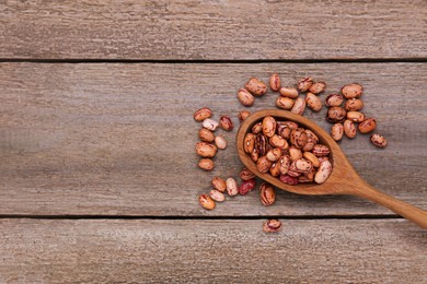 Photo of Spoon and dry kidney beans on old wooden table, flat lay. Space for text