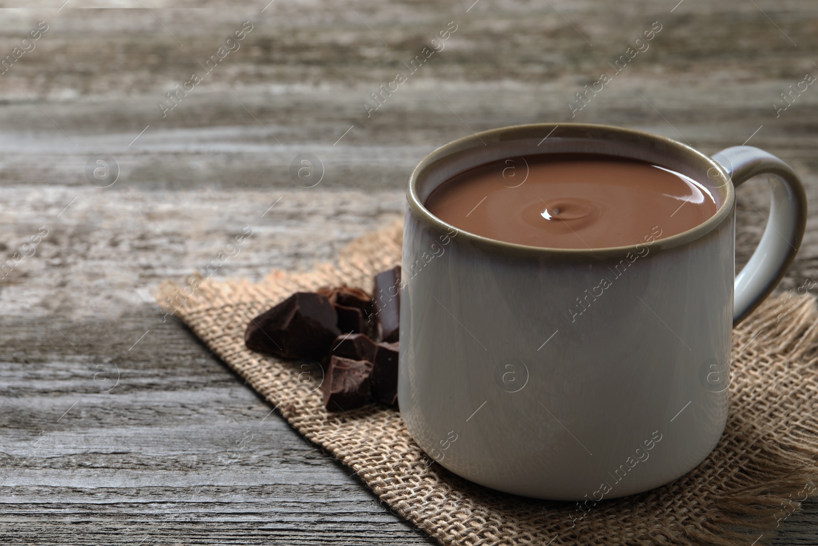 Photo of Yummy hot chocolate in mug on wooden table. Space for text