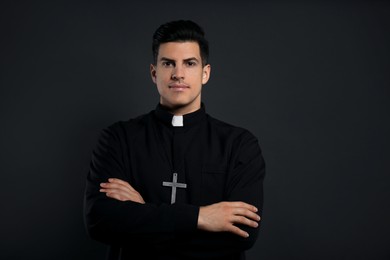 Photo of Priest in cassock with cross on black background