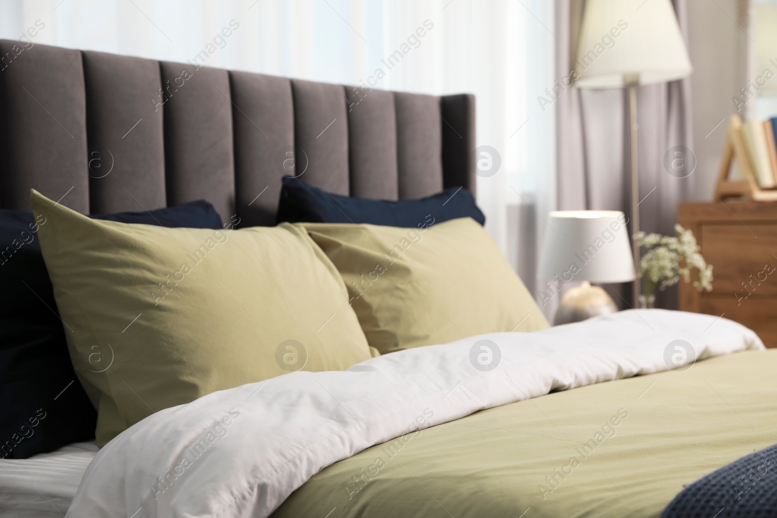 Photo of Comfortable bed with cushions and bedding in room. Stylish interior