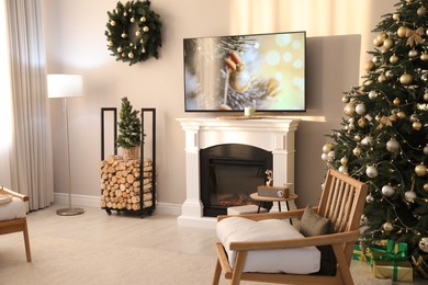 Photo of Modern TV set on light wall in room decorated for Christmas