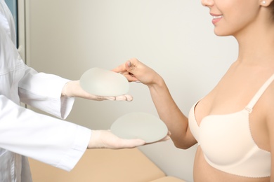 Photo of Doctor showing silicone implants for breast augmentation to patient in clinic, closeup. Cosmetic surgery