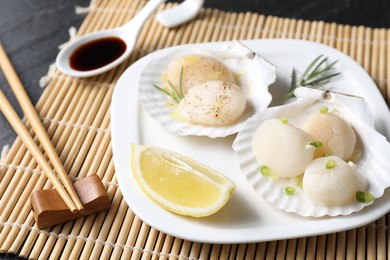 Photo of Raw scallops with green onion, rosemary and lemon on dark table, closeup
