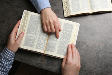 Photo of Humble couple reading Bibles at grey table together, top view