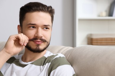 Smiling man sitting on sofa in room. Space for text