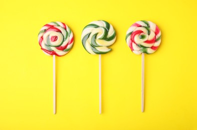 Photo of Colorful lollipops on yellow background, flat lay