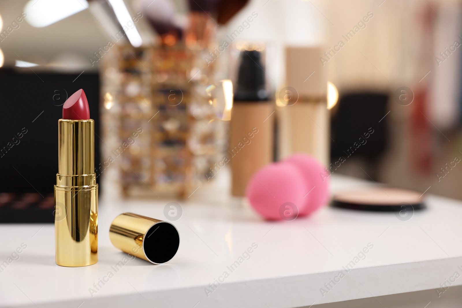 Photo of Red lipstick and other makeup products on white table indoors, selective focus