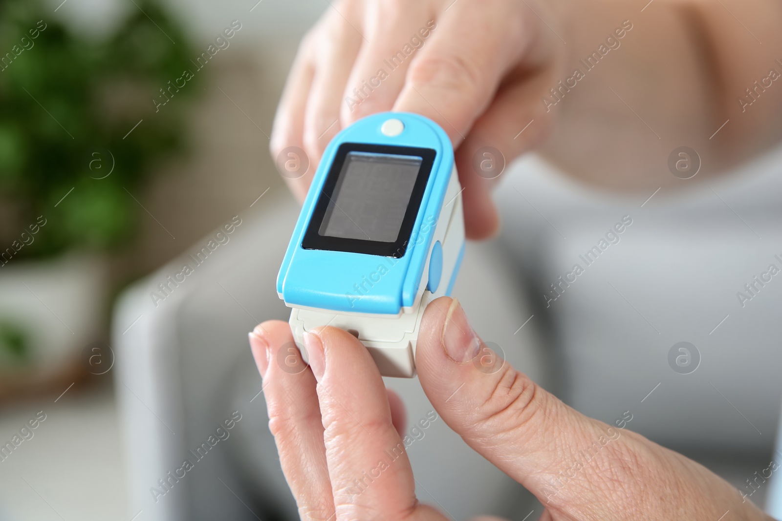 Photo of Mature woman checking pulse with medical device at home, closeup