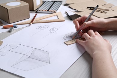 Photo of Woman creating packaging design at light wooden table, closeup