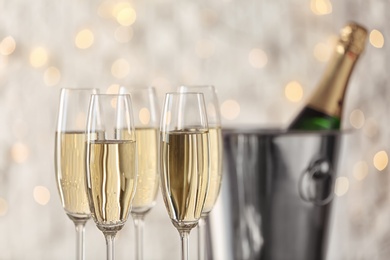 Photo of Glasses with champagne and bottle in bucket against blurred lights