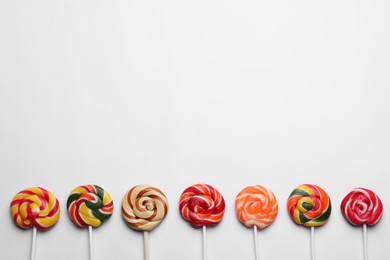 Photo of Sweet lollipops on light background, flat lay. Space for text
