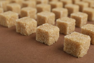 Photo of Brown sugar cubes on color background, closeup