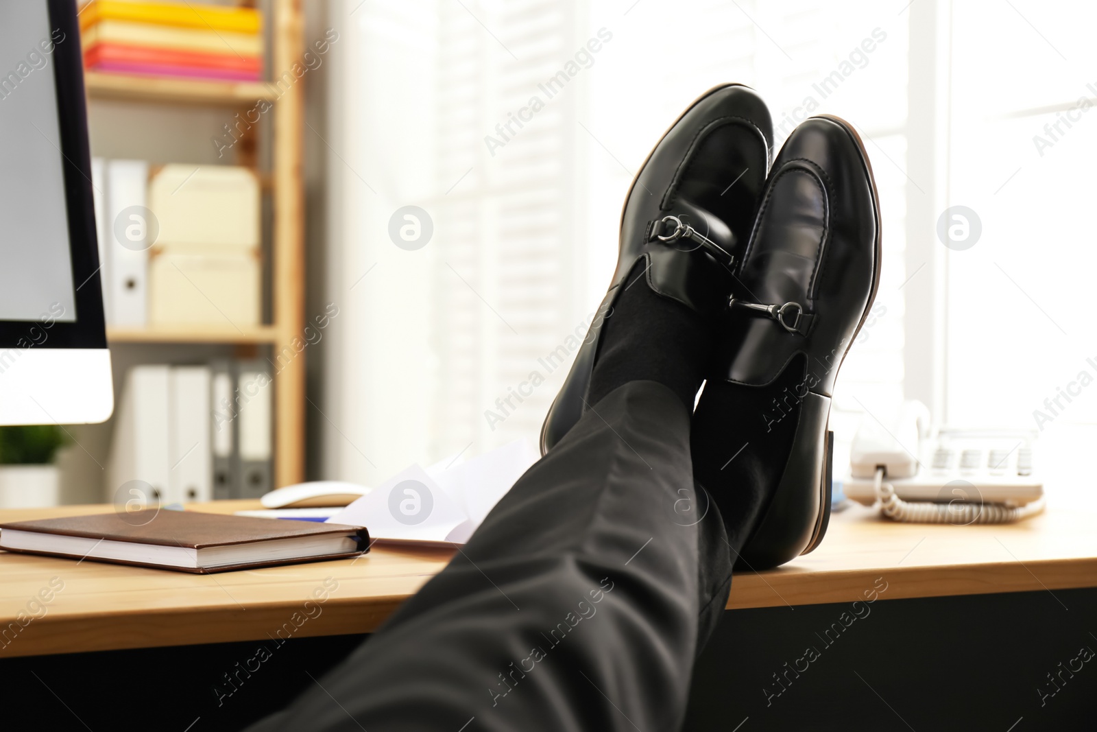 Photo of Lazy employee resting at table in office, closeup of legs