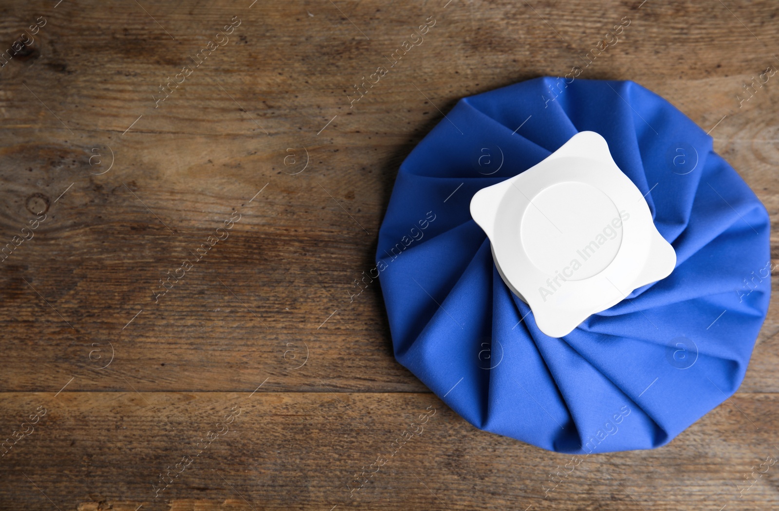 Photo of Ice pack on wooden table, top view. Space for text