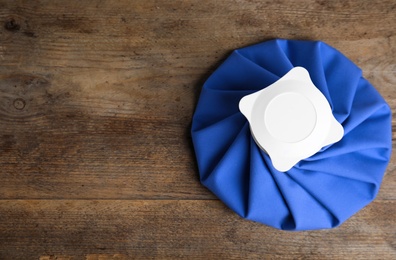 Ice pack on wooden table, top view. Space for text