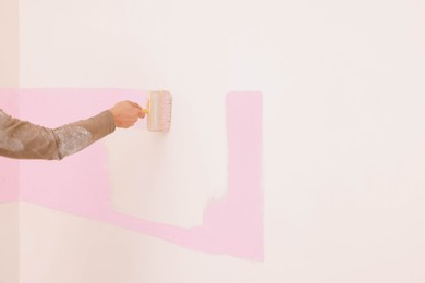Photo of Decorator painting wall indoors, closeup. Space for text