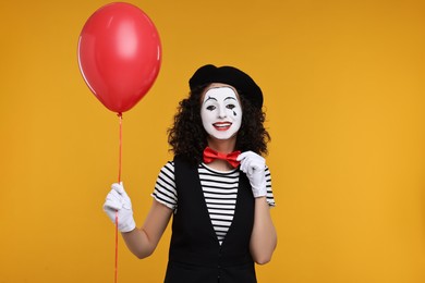 Photo of Funny mine with balloon posing on orange background