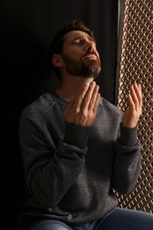Upset man praying to God during confession in booth