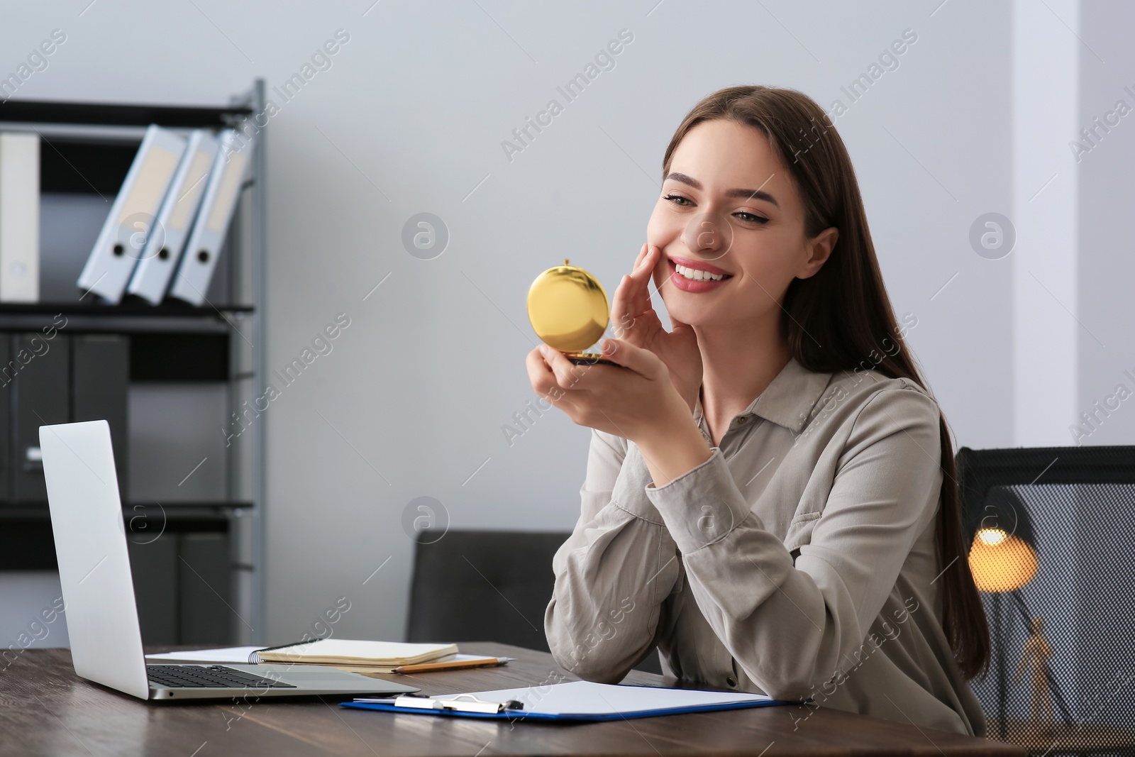 Photo of Young woman looking at herself in cosmetic pocket mirror indoors, space for text