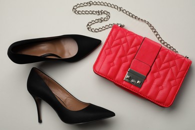 Photo of Pair of elegant high heel shoes and handbag on light background, flat lay