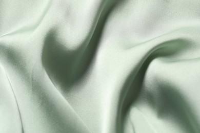 Photo of Texture of light green crumpled silk fabric as background, top view