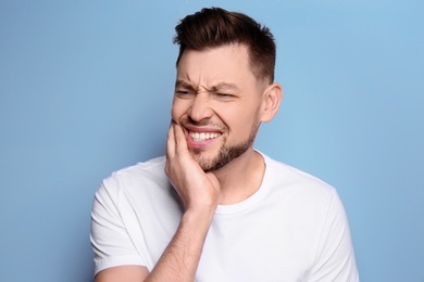 Young man suffering from toothache on grey background