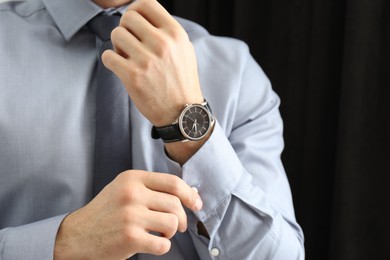 Photo of Man with luxury wrist watch on dark background, closeup