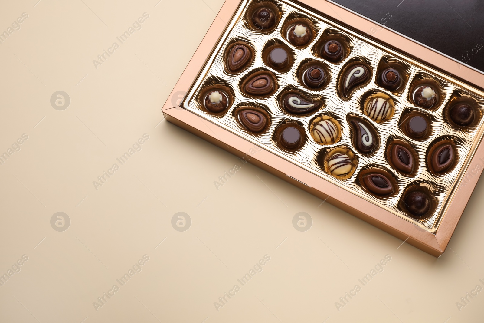 Photo of Box of delicious chocolate candies on beige background, top view. Space for text