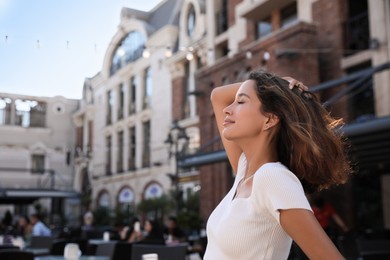 Portrait of happy young woman on city street. Space for text