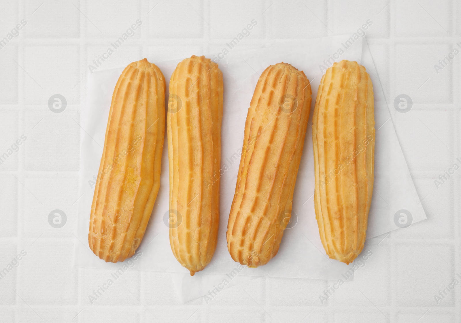 Photo of Delicious eclairs on white checkered table, top view