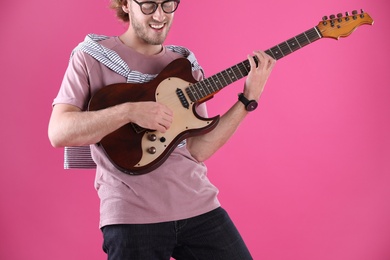 Young man playing electric guitar on color background