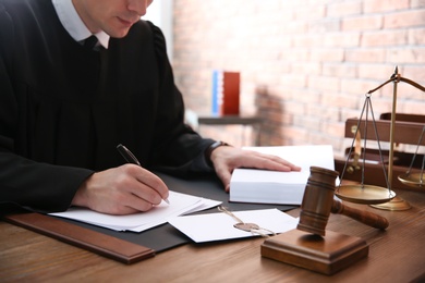 Judge working with papers and gavel on table, closeup. Law and justice concept