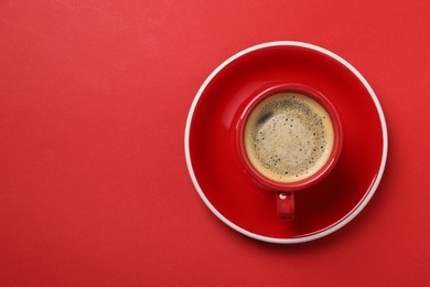 Photo of Tasty coffee in cup on red background, top view. Space for text