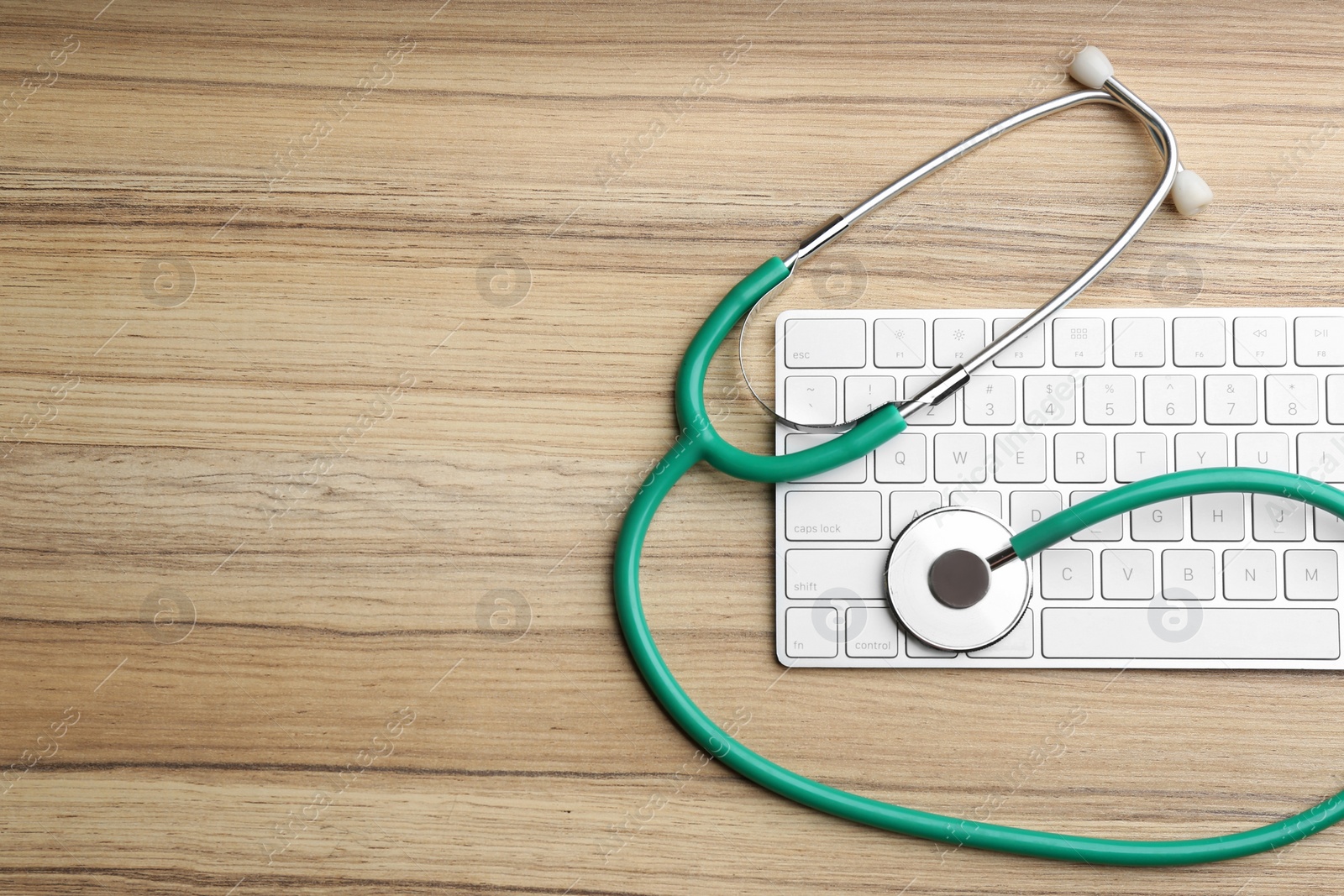 Photo of Keyboard and stethoscope on wooden table, flat lay with space for text. Concept of technical support