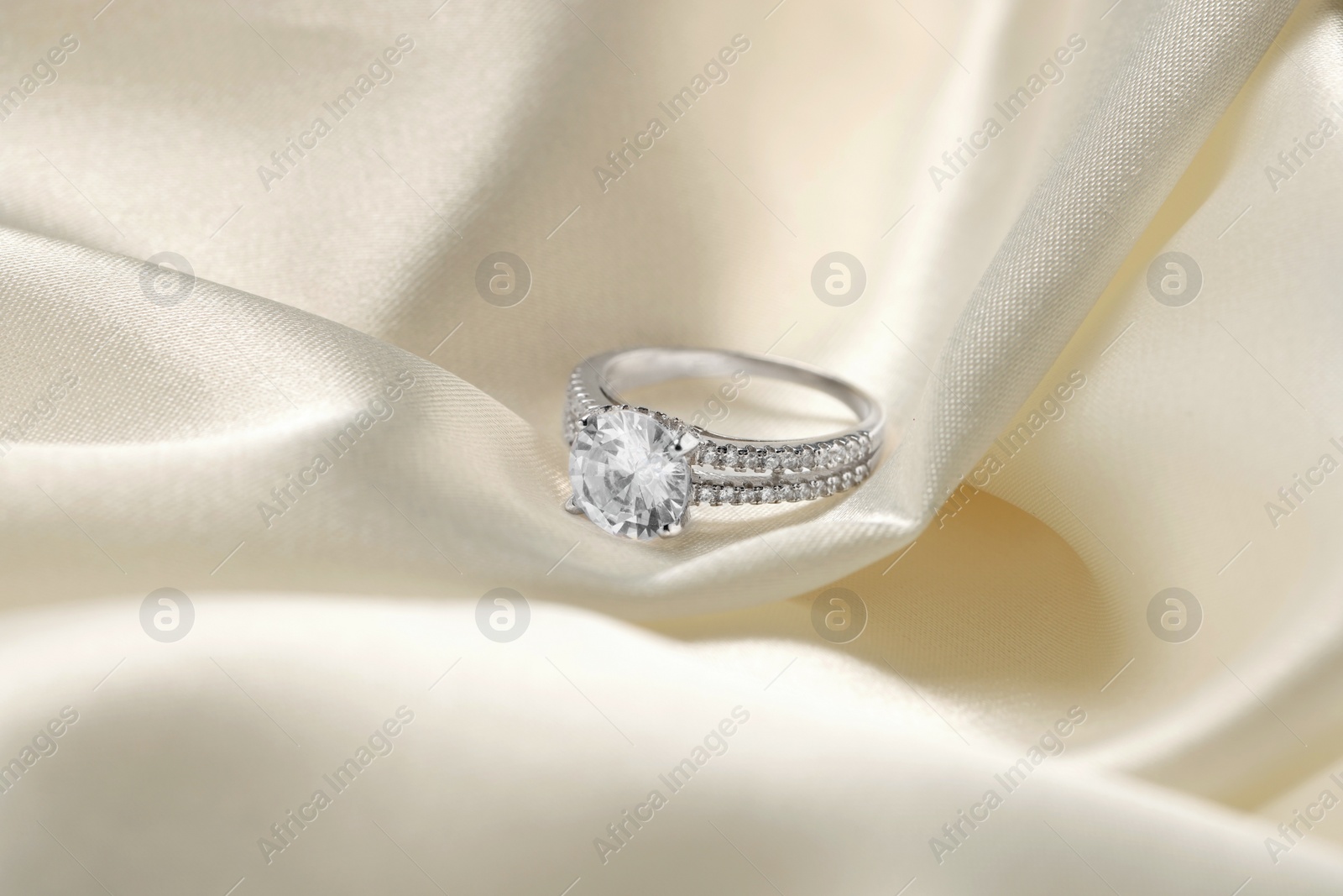 Photo of Beautiful ring with gemstones on white fabric. Luxury jewelry