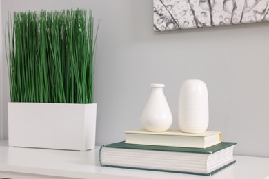 Photo of Potted artificial plant, books and decor on white table indoors