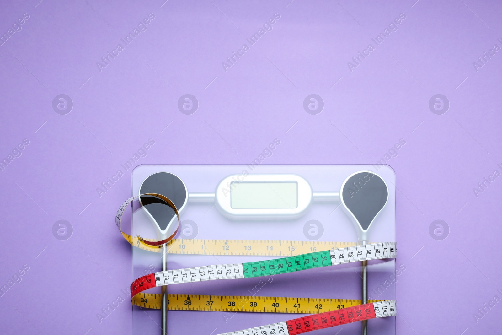 Photo of Electronic scales and measuring tape on violet background, top view. Space for text