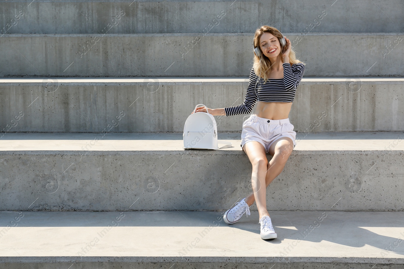 Photo of Young woman with stylish backpack on stairs outdoors. Space for text