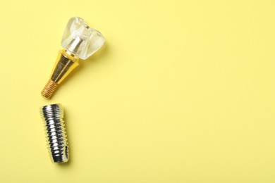 Parts of dental implant on yellow background, flat lay. Space for text